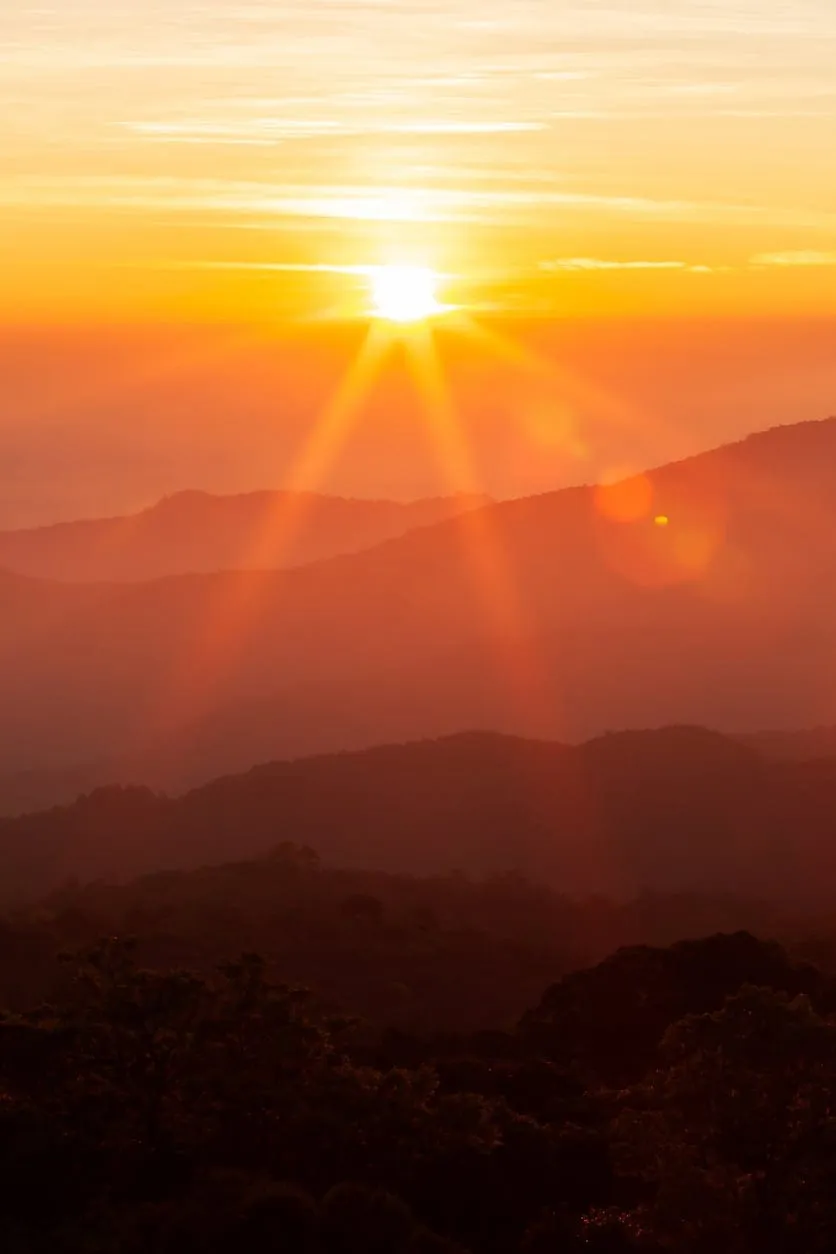 Golden sunrise breaking over layered mountain ridges