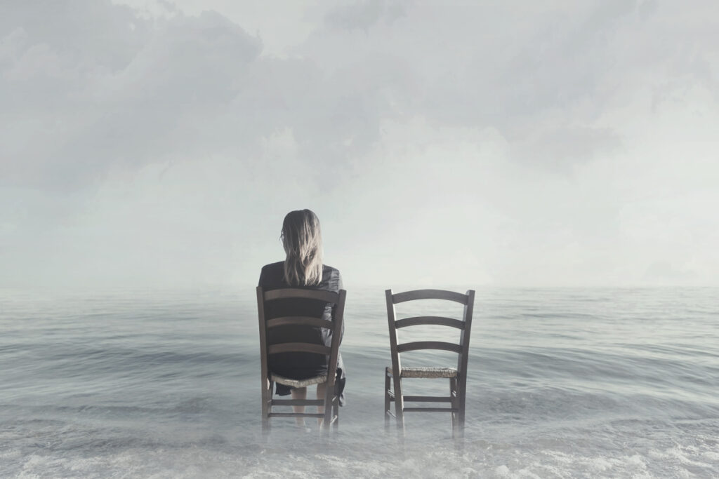 woman sitting alone on one of two chairs on top of water crave affection