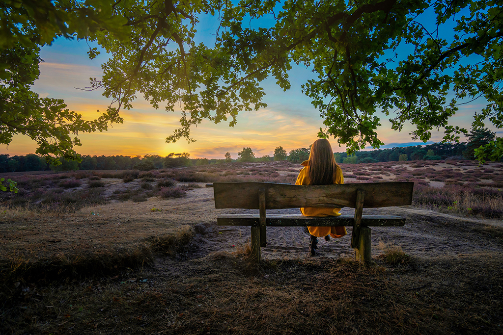 A woman sitting alone on a bench in quiet, reflective thought